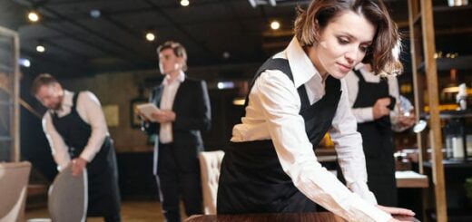 Kellner*in bei der Arbeit. Die Plätze im Restaurant werden gereinigt.