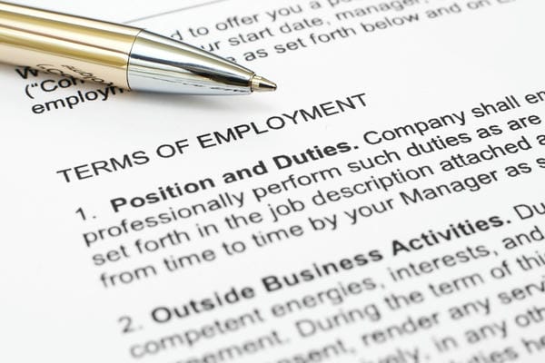 Nahaufnahme eines Kugelschreibers, der auf einem Arbeitsvertrag über der Überschrift „TERMS OF EMPLOYMENT“ liegt.
