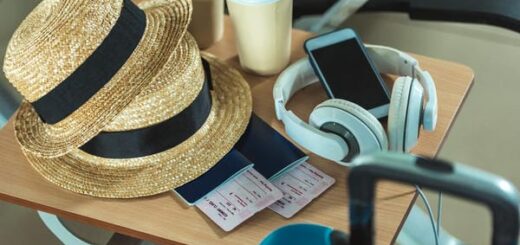 Reiseutensilien wie Strohhüte, Pässe und Kaffeebecher liegen für den Urlaubsantritt während der Betriebsferien auf einem Tisch bereit.