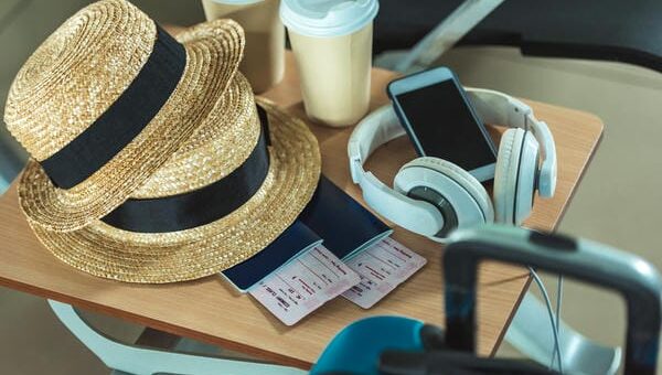 Reiseutensilien wie Strohhüte, Pässe und Kaffeebecher liegen für den Urlaubsantritt während der Betriebsferien auf einem Tisch bereit.