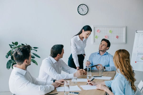 5 Personen sitzen an einem Tisch und halten ein Meeting