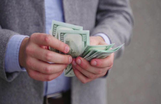 Eine Person in Business-Kleidung zählt Bargeld für das monatliche Einkommen.