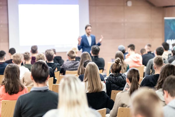 Redner hält einen Vortrag im Konferenzsaal bei einer Veranstaltung für die berufliche Weiterbildung mit Publikum im Konferenzsaal.