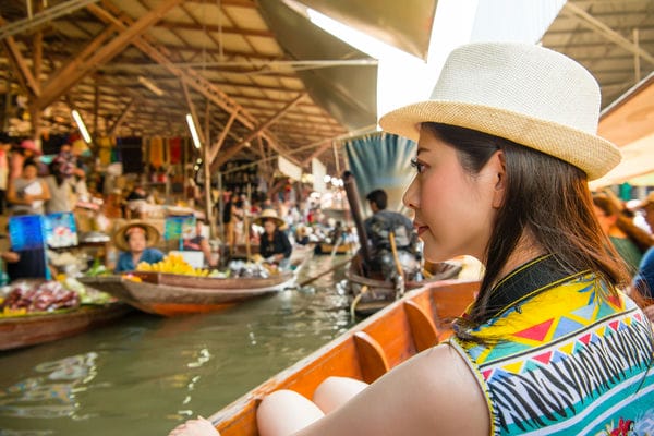 Eine Frau kauft in Thailand via Boot ein.